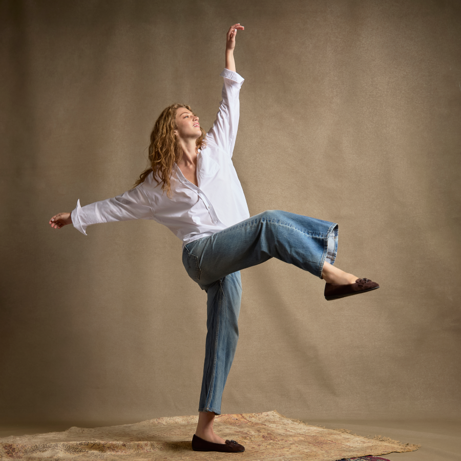woman dancing wearing jeans, white button down and loafers