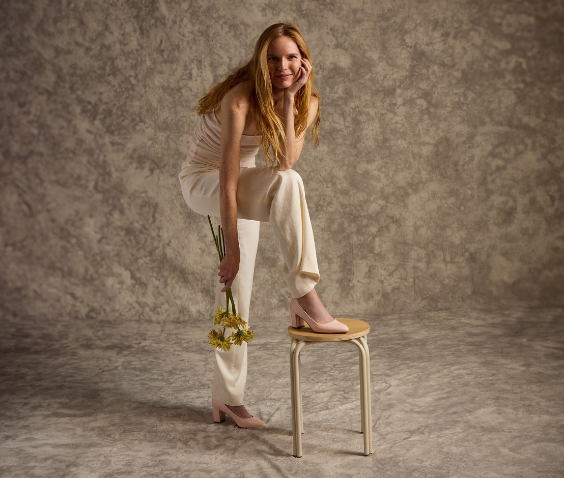 Woman sitting on a stool holding flowers against a textured brown background